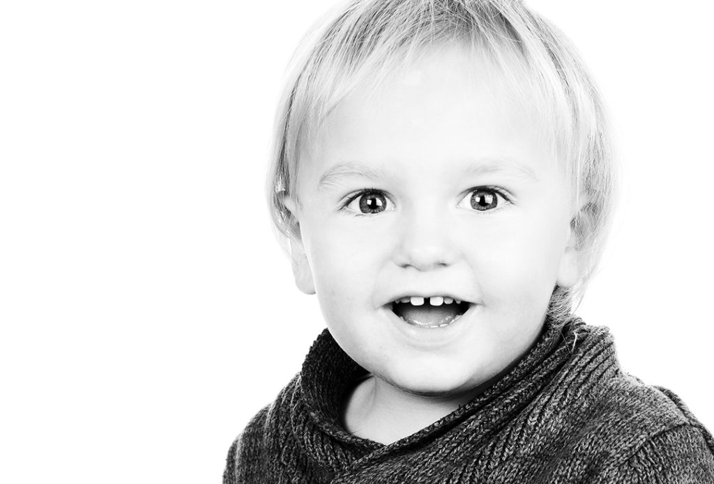 Fröhliches Familienportrait von Sarah Reuther, das ein lachendes Baby zeigt, das in die Kamera blickt.