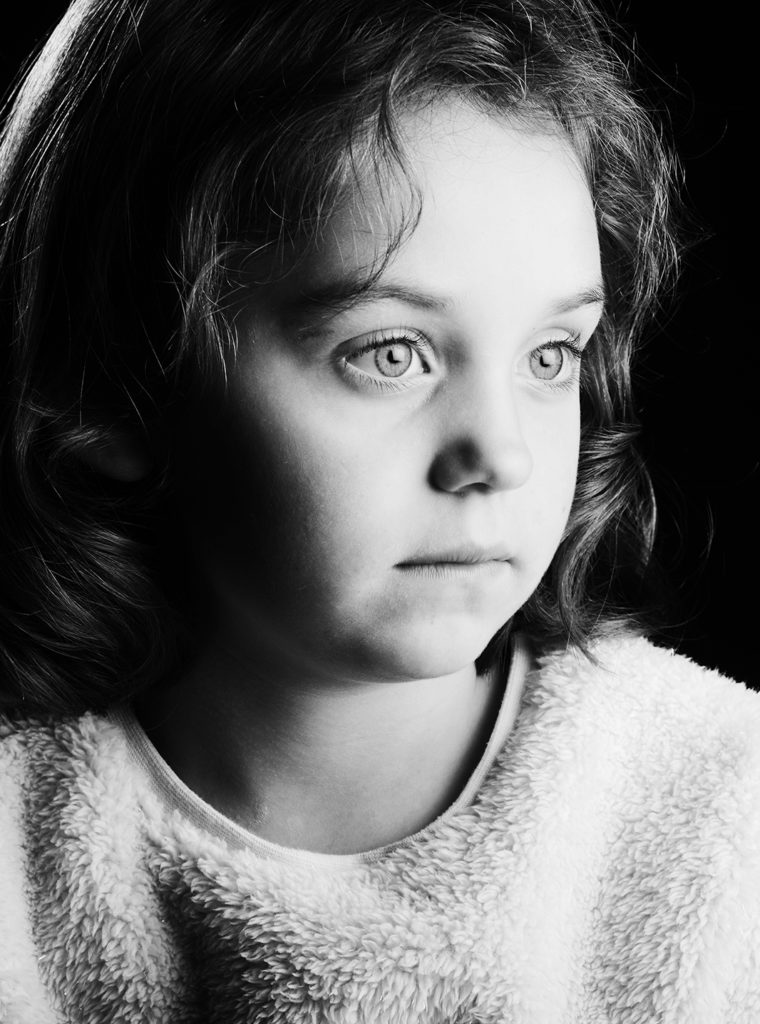 Stilvolles Portrait vom Fotostudio Reuther, das ein Mädchen zeigt, das in die Ferne blickt, eingefangen in einem Low-Key-Stil.