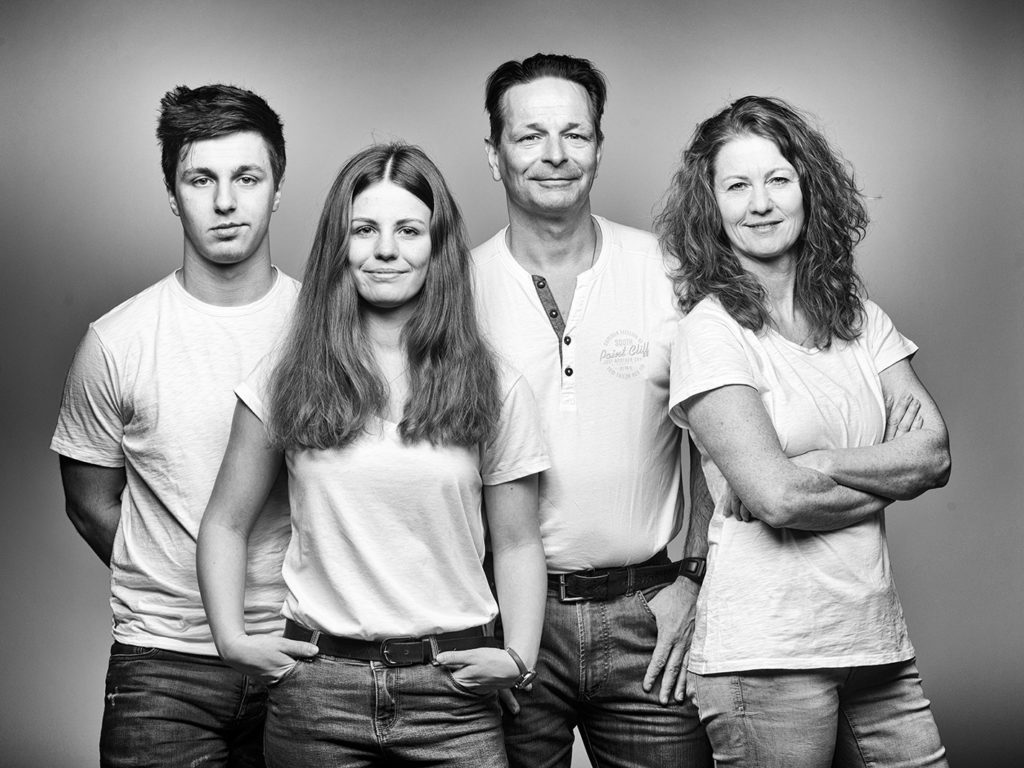 Seriöses Familienportrait vom Fotostudio Reuther, das eine Familie zeigt, die gemeinsam in die Kamera blickt.
