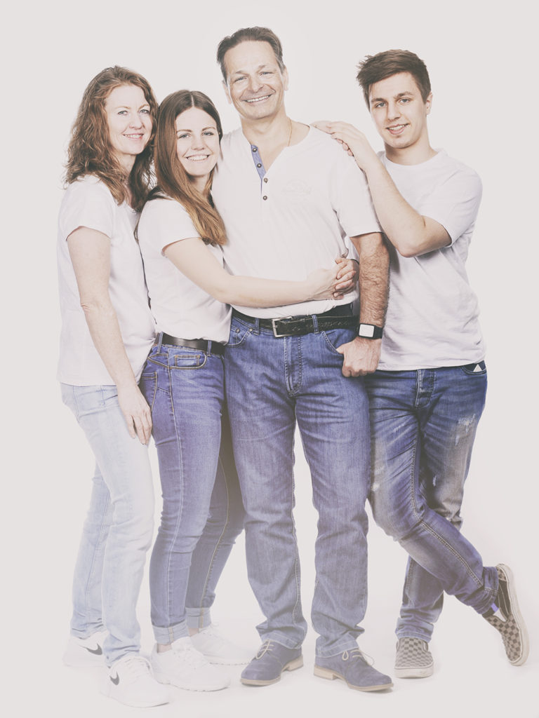 Fröhliches Familienportrait vom Fotostudio Reuther, das eine Familie zeigt, die gemeinsam in die Kamera lacht.