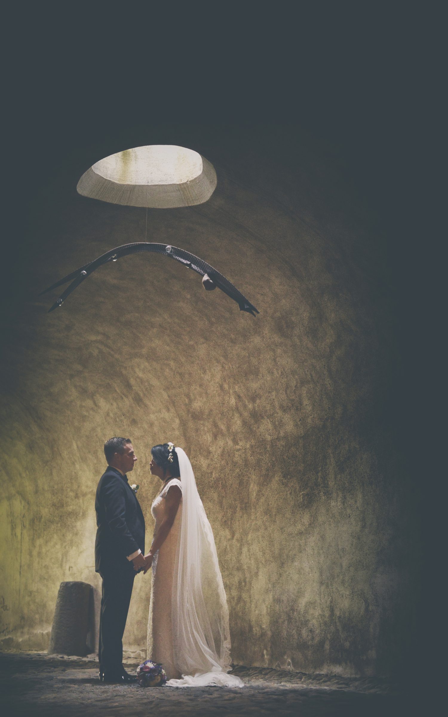 Hochzeit04 Brautpaar im alten Gewölbe, umgeben von historischen Steinmauern, während sie liebevoll miteinander interagieren und eine romantische Atmosphäre schaffen.