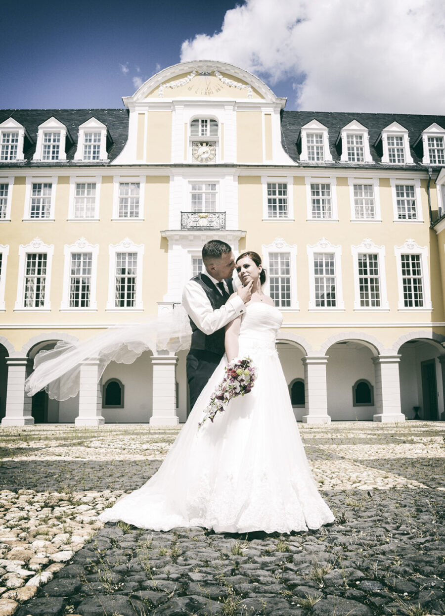 Braut und Bräutigam in einem romantischen Portrait, beide lächeln glücklich und strahlen Liebe aus.