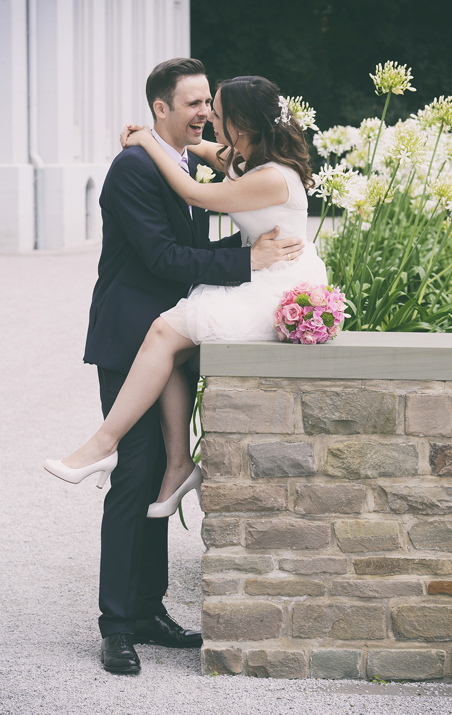 Hochzeit 15 Brautpaar, das auf einer Mauer steht und sich leidenschaftlich küsst, umgeben von einer romantischen Atmosphäre.