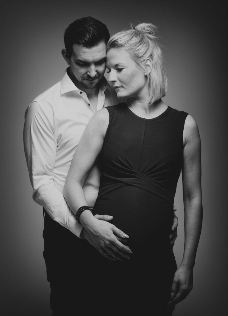 Romantisches Familienportrait vom Fotostudio Reuther, das ein Paar zeigt, das sich in eleganter Kleidung umarmt.