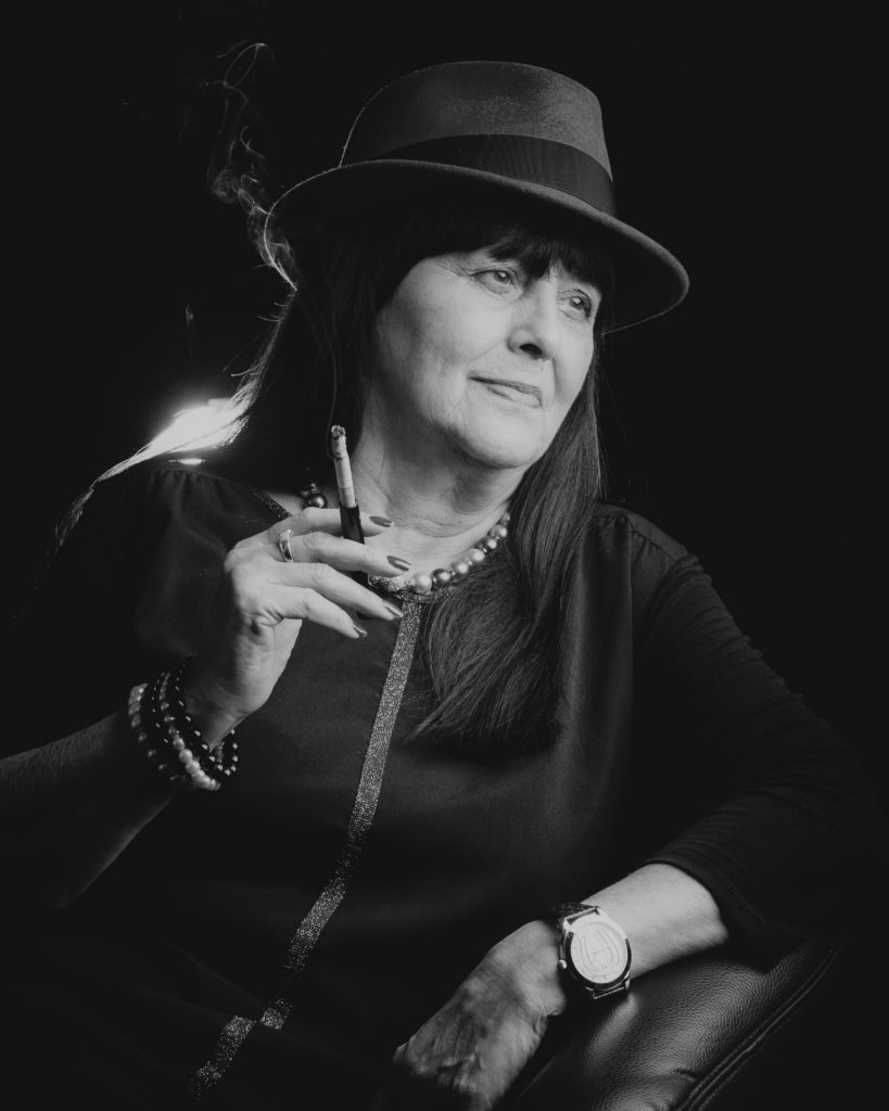Portrait einer Frau mit Hut und Zigarette in Schwarz-Weiß.