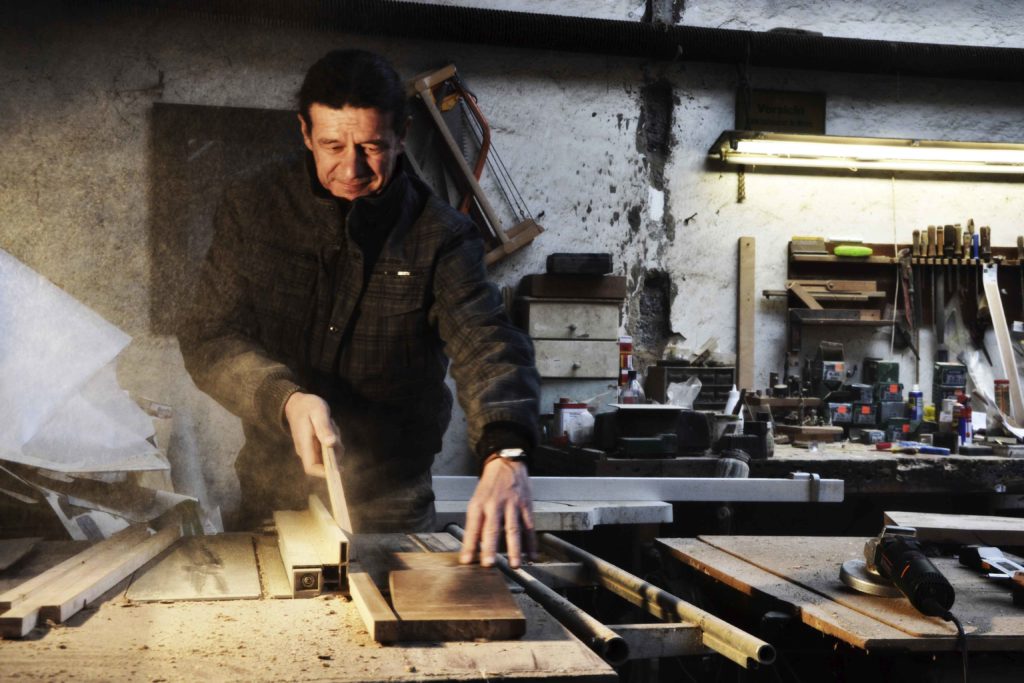 Schreinermeister bei der Arbeit mit der Tischsäge, während er Holzstücke für ein Projekt in seiner rustikalen Werkstatt zuschneidet.