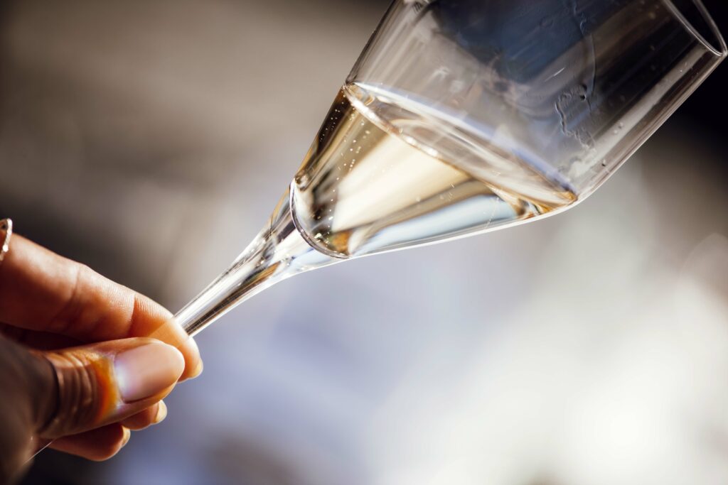 Detailaufnahme eines Sektglases, das die feine Struktur des Glases und den sprudelnden Sekt zeigt.