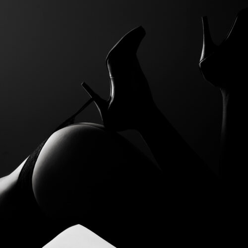 Akt (3) Der Po einer Frau in High Heels, eingefangen in einem Schwarz-Weiß Low-Key-Stil, der die Kurven und Eleganz betont und eine geheimnisvolle Atmosphäre schafft, gestaltet im kreativen und künstlerischen Ansatz von Fotostudio Reuther.