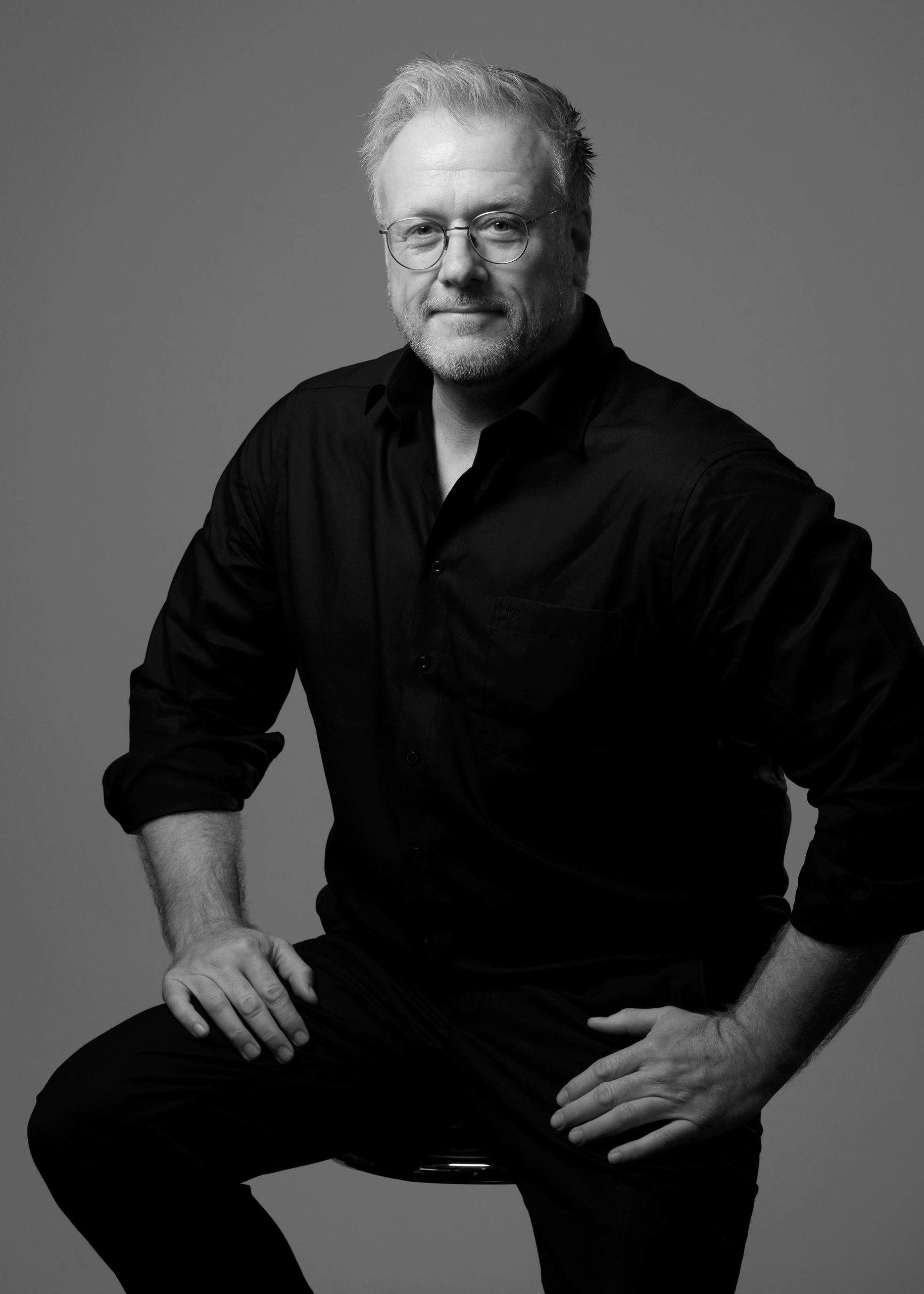 Portrait eines Mannes in Schwarz-Weiß, das seine Charakterzüge und Ausstrahlung eindrucksvoll zur Geltung bringt, eingefangen im künstlerischen und stilvollen Ansatz von Fotostudio Reuther.