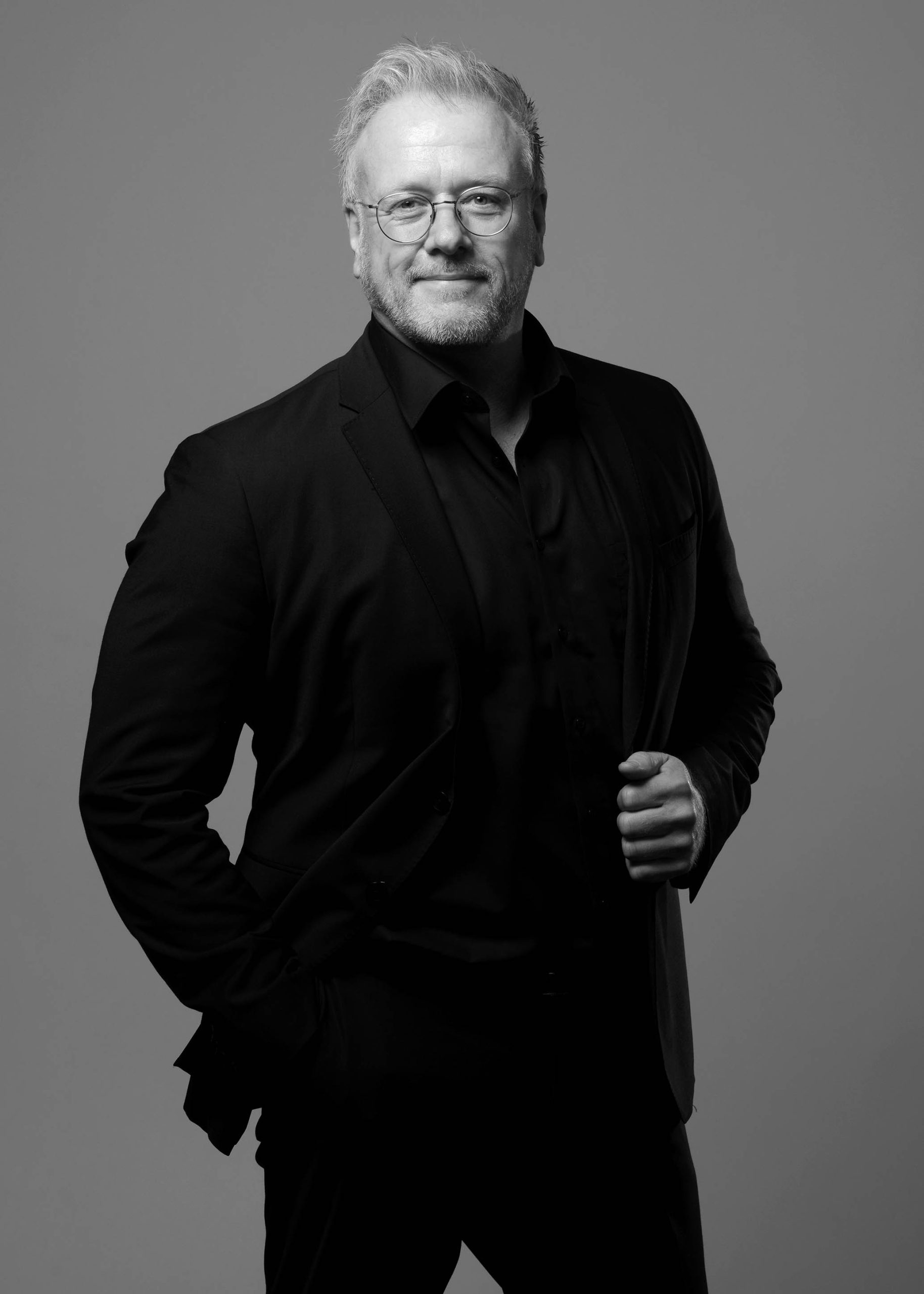 Portrait eines Mannes in Schwarz-Weiß, das seine Charakterzüge und Ausstrahlung eindrucksvoll zur Geltung bringt, eingefangen im künstlerischen und stilvollen Ansatz von Fotostudio Reuther.