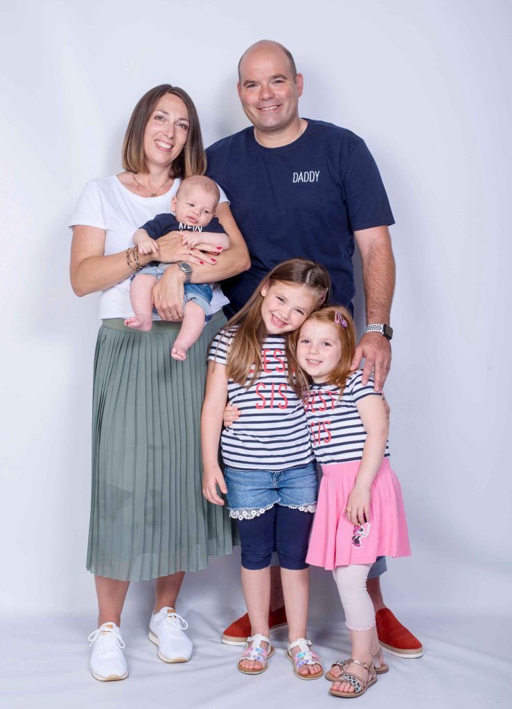 Süßes Familienportrait vom Fotostudio Reuther, das eine Familie mit Baby im Studio vor einem weißen Hintergrund zeigt.