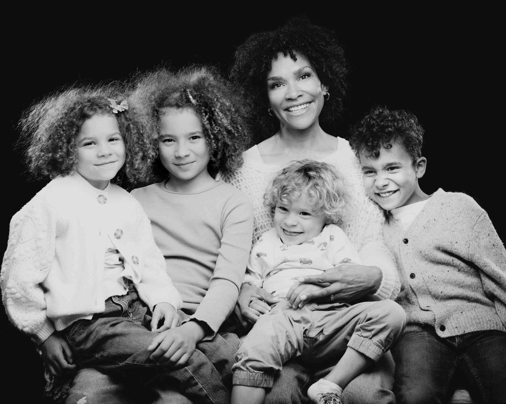 Künstlerisches Familienportrait von Sarah Reuther, das eine Familie in Schwarz-Weiß vor einem schwarzen Hintergrund zeigt.