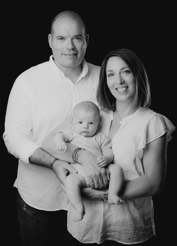 Familienportrait im Studio mit einer schwangeren Frau und einem Baby.