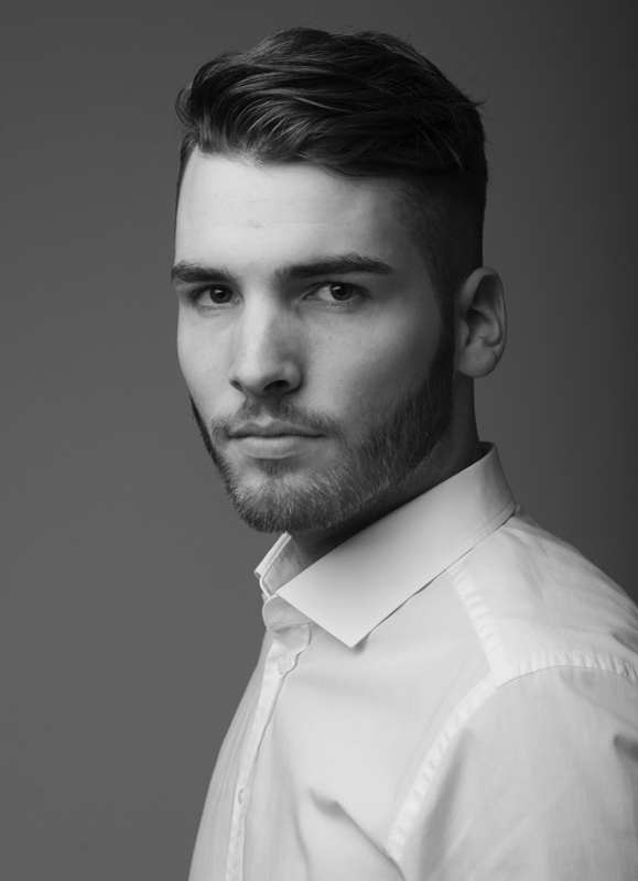 Schwarz-Weiß-Portrait eines jungen Mannes im Business-Look, das seine Professionalität und Entschlossenheit widerspiegelt. business