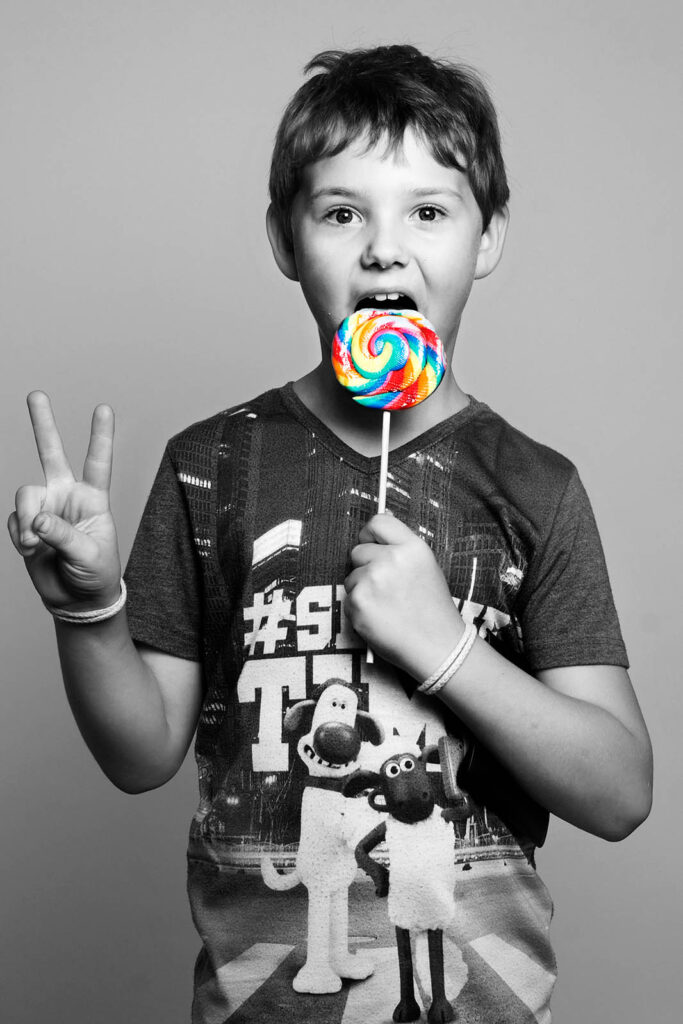 Schwarzweiß Portrait eines Jungen mit einem Lolly im Fotostudio Reuther